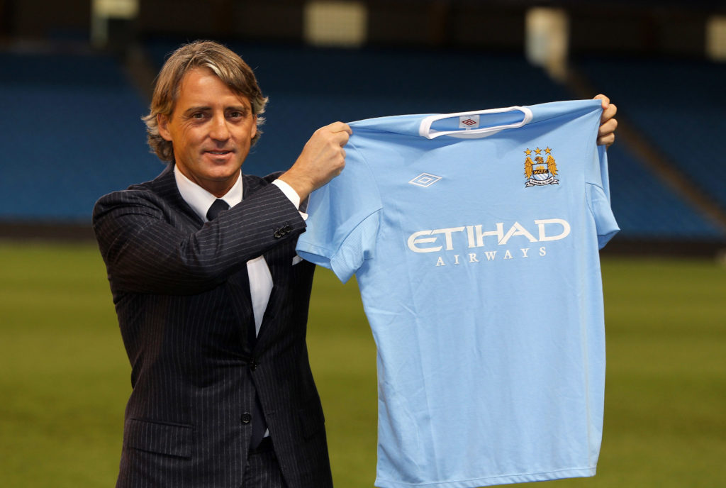 Roberto Mancini posing for a photo with Manchester City shirt after becoming their manager in 2009
