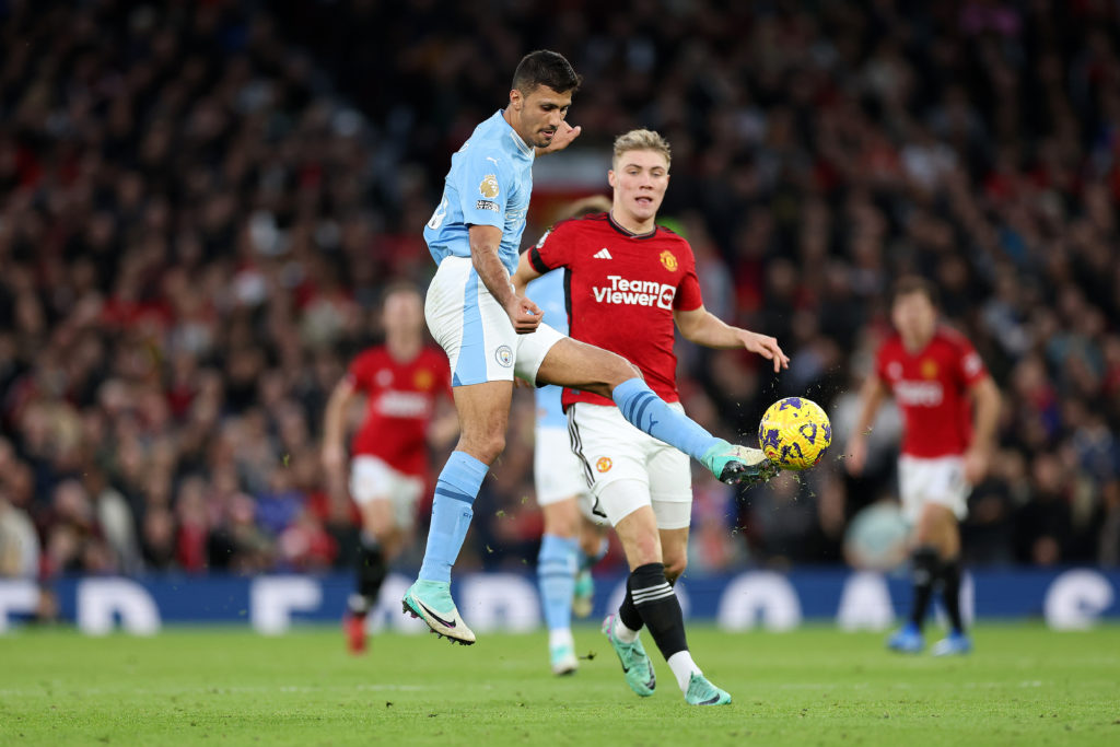 Rodri of Manchester City passes the ball whilst under pressure from Rasmus Hojlund of Manchester United during the Premier League match between Manchester United and Manchester City at Old Trafford on October 29, 2023