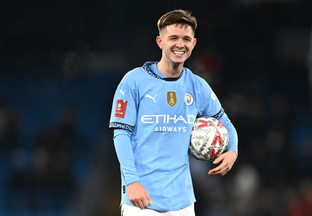 James McAtee holding a football during Manchester City v Salford City.