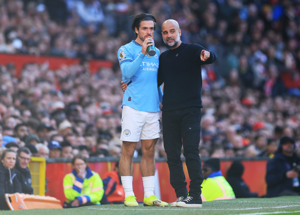 Jack Grealish and Pep Guardiola chatting on the sideline during Manchester United FC v Manchester City FC