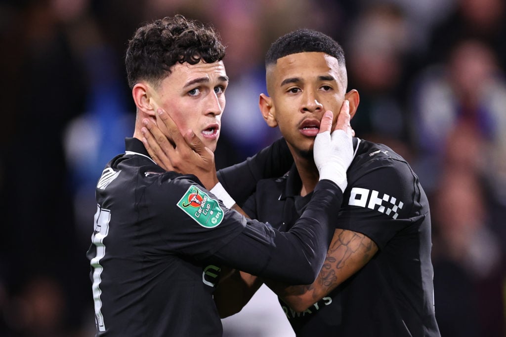 Phil Foden and Savinho with their hands on each other's faces during Huddersfield Town v Manchester City